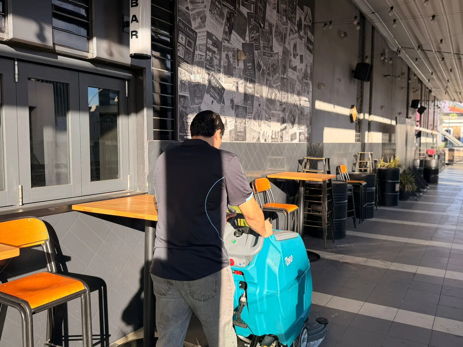 SJV Cleaning technician machine-scrubbing the floor of a covered outdoor bar
