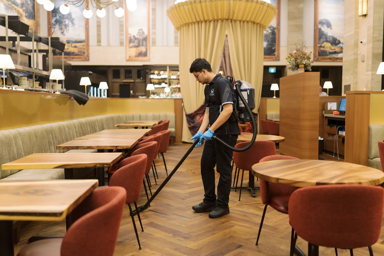 SJV Cleaning team member vacuuming a restaurant with a backpack vacuum